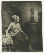 Woman sitting half dressed beside a stove